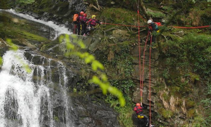 Bearded men adventures canyoning down a waterfall, snowdonia